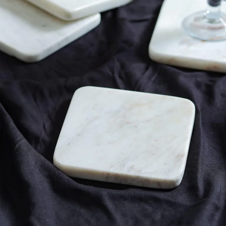 Elegant set of 4 white marble coasters, perfect for protecting surfaces with style. Each coaster has a smooth finish and natural stone texture, adding a touch of sophistication to any setting. 3